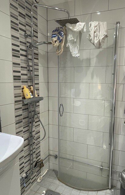 Badrum med duschglasvägg, handdukar, hygienprodukter och duschtillbehör. Enkelt och modernt inrett.