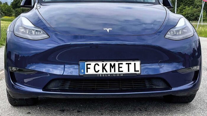 Blå Tesla med anpassad registreringsskylt, framifrån, på en väg vid dagsljus.