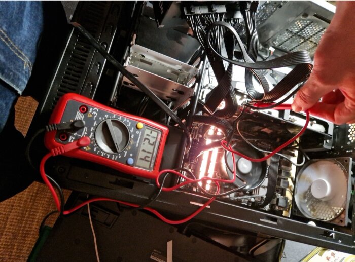 Datordiagnostik eller reparation, multimeter används, interna komponenter synliga, kablage och lysdioder aktiverade.