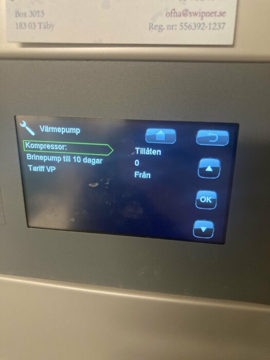 Digital display för värmepump, med kompressorinformation och navigeringsikoner, belägen i Täby.