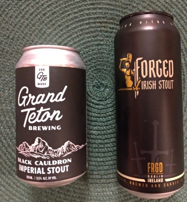 Två ölburkar, Grand Teton och Forged Irish Stout, på strukturerad yta.