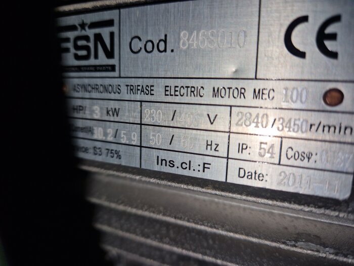 Metallic data plate på en elektrisk motor som visar specifikationer såsom effekt, spänning, varvtal och tillverkningsdatum.