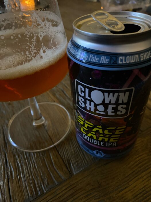 Ölglas halvfullt med öl, burk "Clown Shoes Double IPA", träyta.