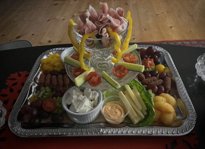 Ett fat med blandade snacks: kött, ostar, frukt och grönsaker, serverade för en fest.