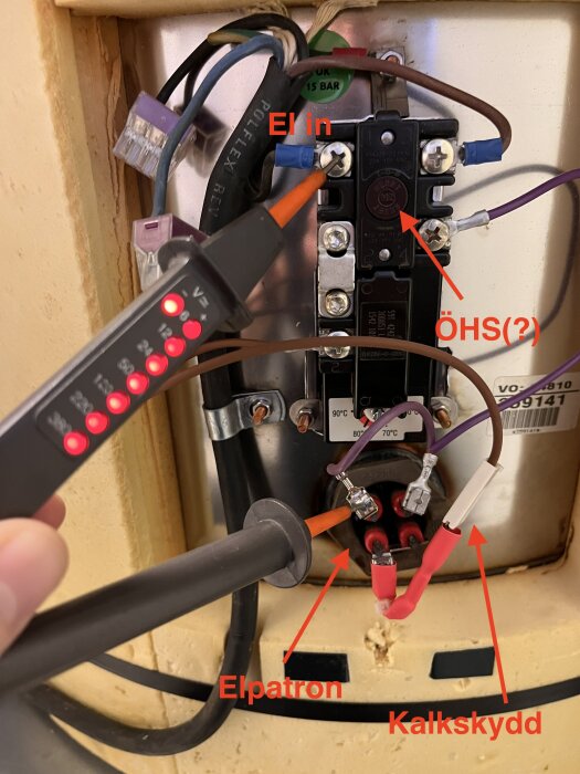 Elpatron för varmvattenberedare med ledningar, kontrollinstrument och markeringstexter. Anslutningar och något skydd syns.