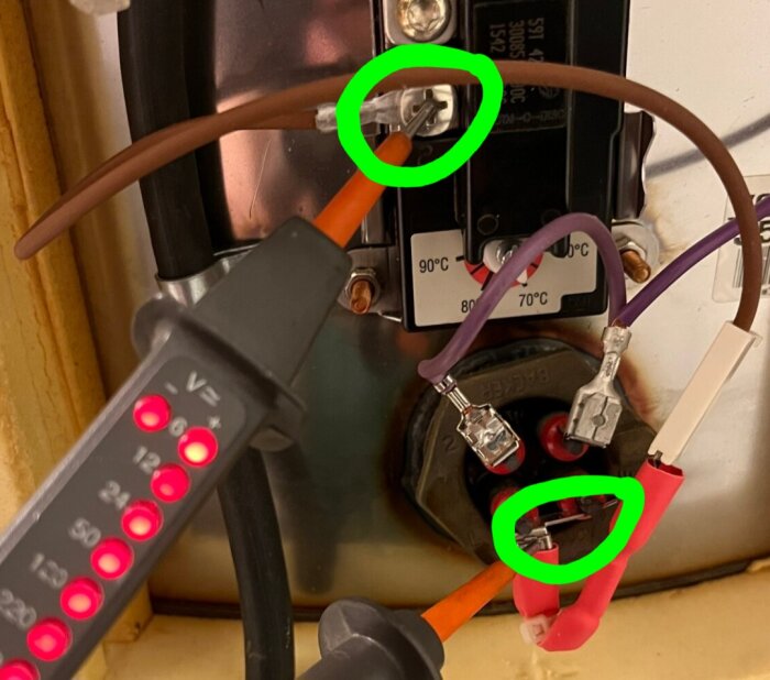 Elektrisk anslutning med synlig spänningstestare och potentiell farlig ledningsfel markerad med gröna cirklar.