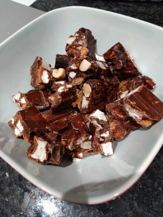 Skål med hackad Rocky Road-fudge, choklad, nötter, marshmallows, marmorerad granitbänk bakgrund.