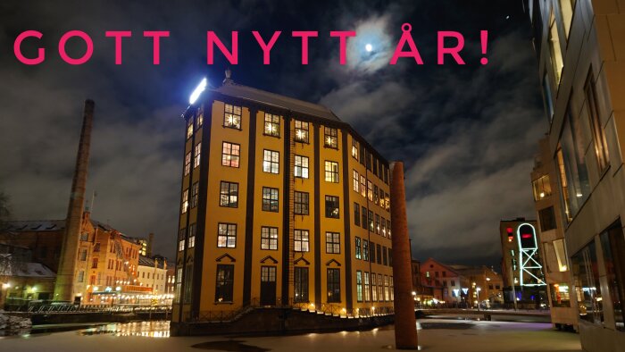 Natt, industriellt byggnadskomplex, upplyst, reflekterat i vatten, "Gott Nytt År" text, snö, molnig himmel, neonskylt.