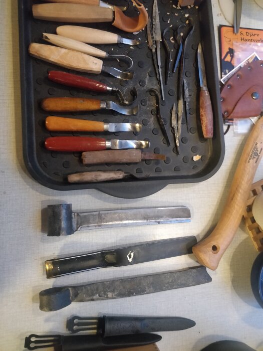 Samling av snickeriverktyg: mejslar, tänger och knivar på ett bord, vissa i fodral.