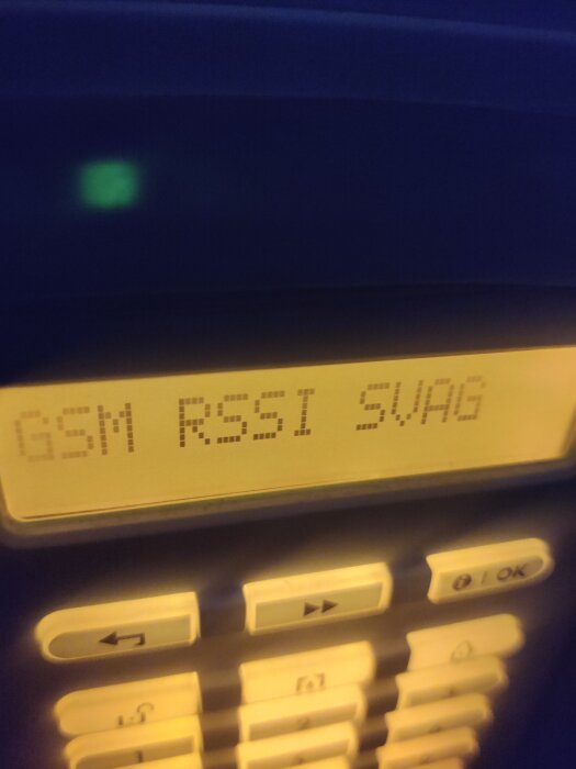 LCD-display visar "GSM RSSI 5VÄG". Knappar nedanför skärmen. Mörk bakgrund. Maskinellt interface, anslutningsstyrka indikeras.