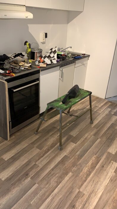 Kök under renovering med verktyg och oordning på bänkar och golv.