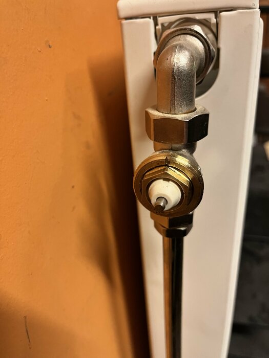 Radiatorventil närbild, anslutning, mässingskoppling, vit element, värmesystem, inomhus, oskarp bakgrund.
