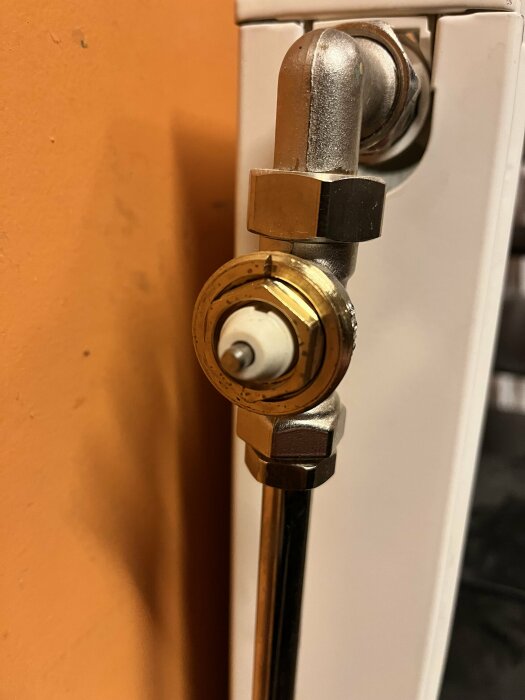 Radiatorventil och termostatanslutning på en värmeelement, i närbild, inomhusmiljö.