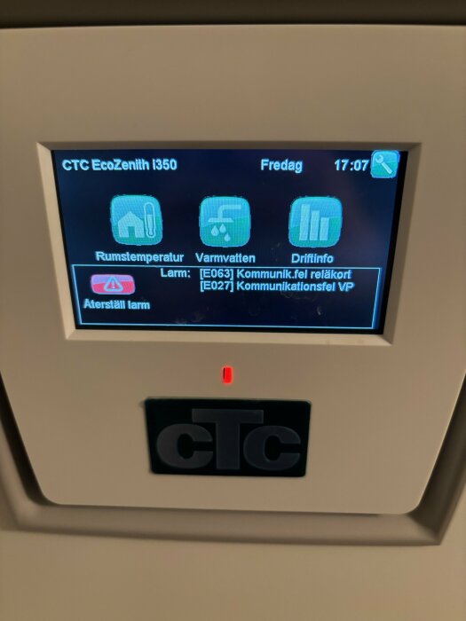 CTC EcoZenith i350 styrenhet visar alarm för kommunikationsfel, rums- och varmvattenstatus, tid och dag.