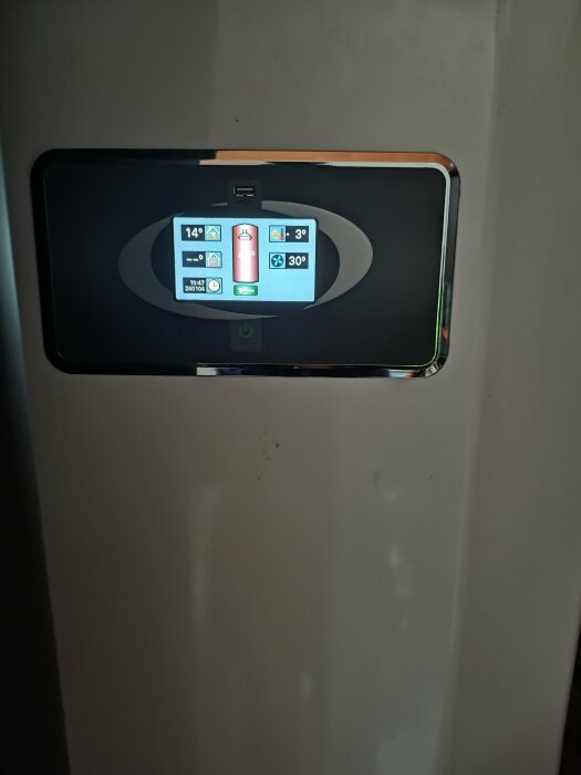 Digital termostatpanel med temperaturindikatorer, batteristatus, klocka och inställningsikoner. Väggmonterad, modern design.