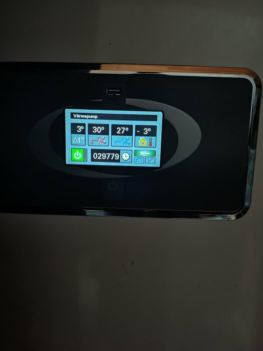 Display för värmepump som visar temperaturinställningar och driftinformation på en digital skärm.