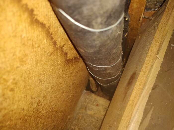 Metallrör nära träytor och brun isolering. Utseendet tyder på ett oisolerat vindutrymme eller liknande.