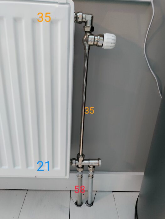Värmeelement med termostat och anslutningsrör, numrerade mätningar indikerar kanske dimensioner eller avstånd.