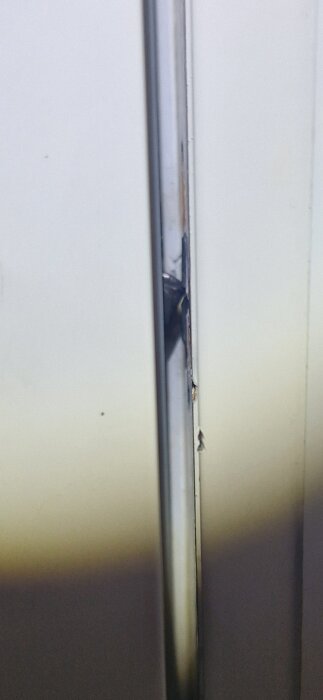 En dörr eller panel med en defekt: sliten kant, skada, reflektioner, skuggor, och vit bakgrund.
