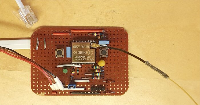 Elektronikprototyp på kopplingsdäck med Wi-Fi-modul, komponenter, ledningar, lödningar på träbakgrund.