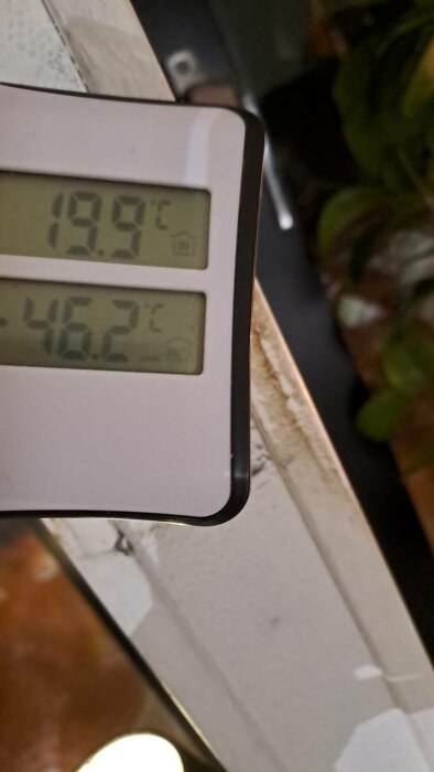 Digital termometer visar inomhustemperatur på 19.9°C och utomhustemperatur på 46.2°C. Oskarp bakgrund.
