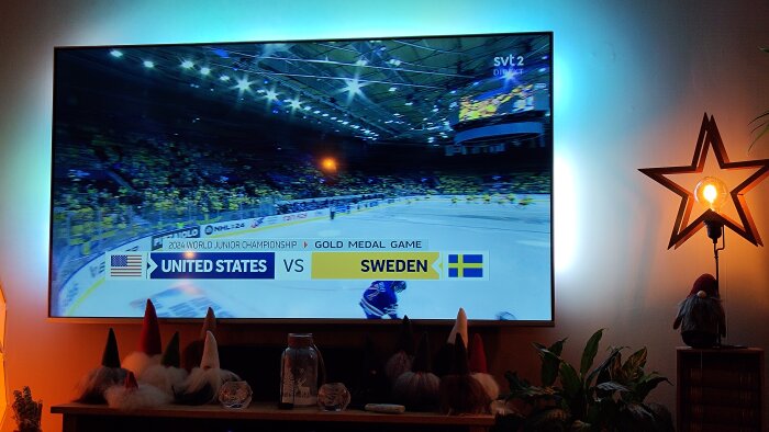 TV-skärm visar ishockeymatch mellan USA och Sverige, inramat av inredningsdetaljer och julpynt.