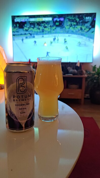 Öl i ett glas och burk, ishockeymatch på TV i bakgrunden, mysig stämning, hemmiljö.