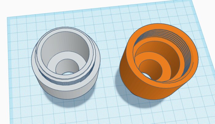 Två 3D-modellerade koniska objekt på en rutig bakgrund, kanske för 3D-skrivning eller CAD-design.