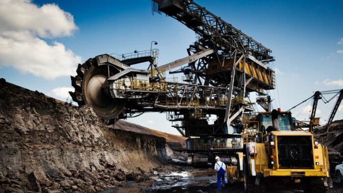 Stor gruvutrustning, hjulgrävare på dagbrott, arbetare och gruvmaskiner, industriell landskap, blå himmel.