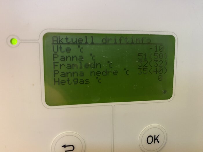 LCD-display visar driftinformation för värmesystem med temperaturvärden och status. Green indikatorlampa lyser.