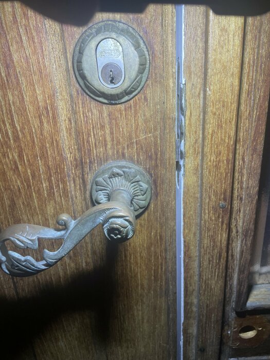 Gammal dörr med lås, Assa nyckelhål, detaljerad handtag, trätextur, belysning ovanifrån.