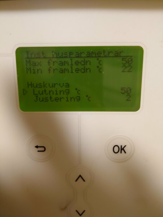 LCD-display visar husparametrar, knappar under för navigering och inställningar. Text på svenska. Potentiellt en värmeregulator.