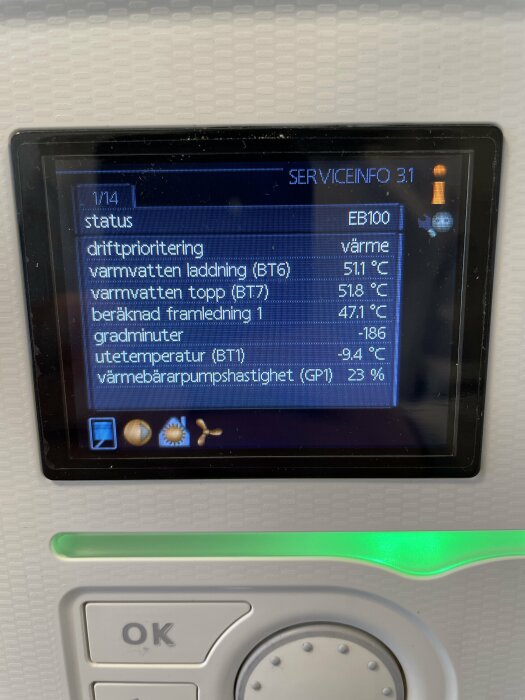 Digital skärm visar värmepumpsstatus med temperaturer och värmebarapumpshastighet, omgiven av vit plast.