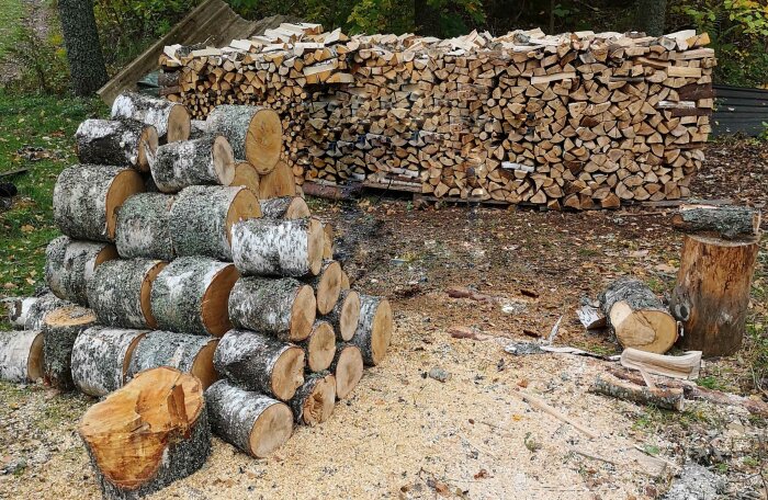 Staplad ved, kluven ved, björkved, yxa, höst, uteplats, träbearbetning, förberedelse för vintern, vedhög.