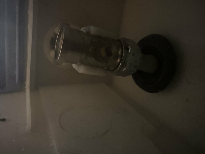 Mörk bild av en vattenventil på en vägg, industriell känsla, dålig belysning, grov textur.