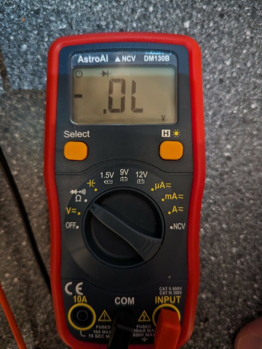 Digital multimeter, röd och svart, elektriska mätningar, skärmläsning visar "-0.L", grå bakgrund.