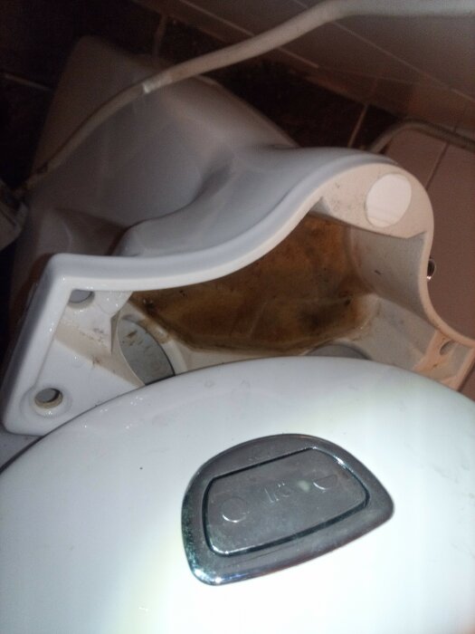 Skadad, smutsig toalettstol med öppet lock och kablar runt, i behov av rengöring och reparation.