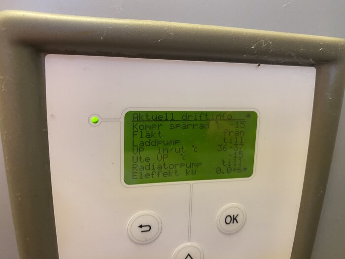 Displaypanel för värmesystem, knappar, grönt statusljus, på svenska, spindelnät i hörnet.