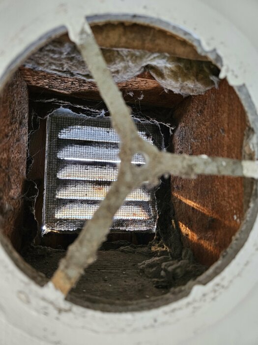 Ett söndrigt ventilationsrör visar isolering och nät; tecken på förfall och försummelse.
