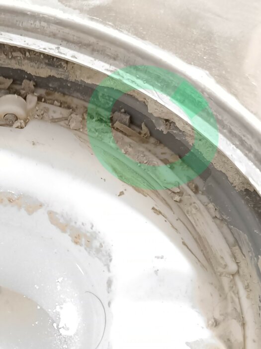 Bilden visar en smutsig köksho med grönt markering på skada eller smutsansamling; behöver städning eller underhåll.