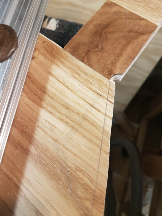 Träkonstruktion och aluminiumprofil nära; detaljbild med sågspån.
