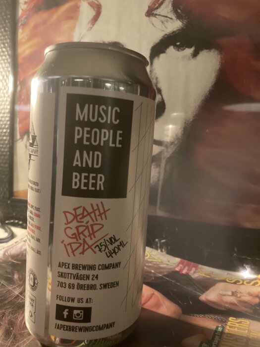 Ölburk från Apex Brewing med texten "Music People And Beer", "Death Grip IPA", bakgrund affisch med ansikte.