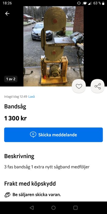 Industriell bandsåg till salu för 1300 kronor, med extrablad inkluderat, framför en bil och byggnad.