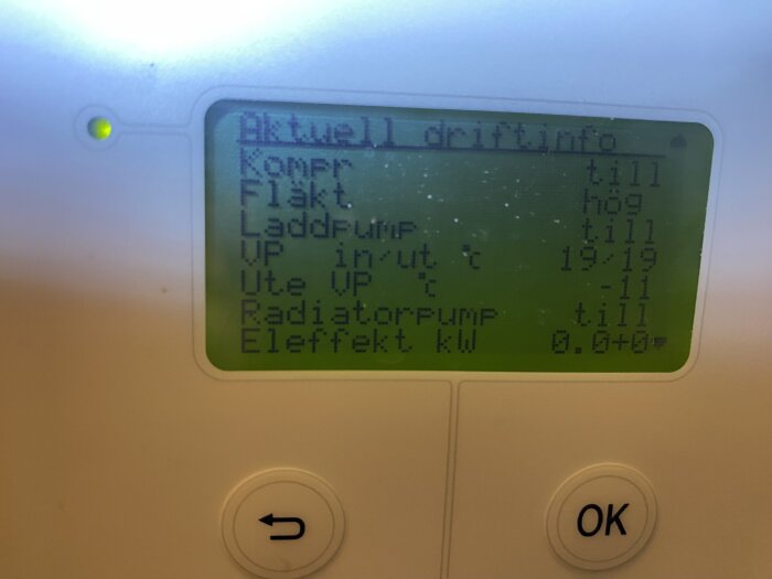 LCD-skärm på enhet, visar driftinformation, temperaturer, grön status-indikator, svenska texter, knappar för navigering.