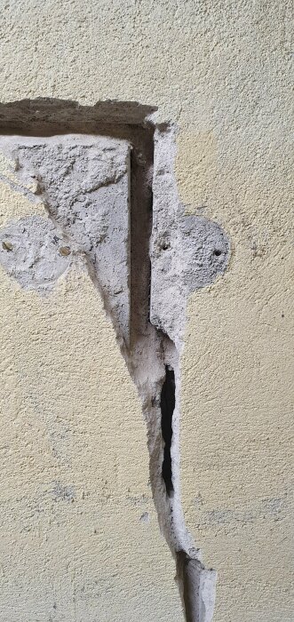 Sprucken puts på vägg visar underliggande lager och konstruktion, behov av reparation synlig.