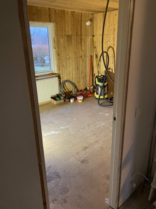 Ett rum under renovering med träväggar, verktyg och renoveringsmaterial synliga.