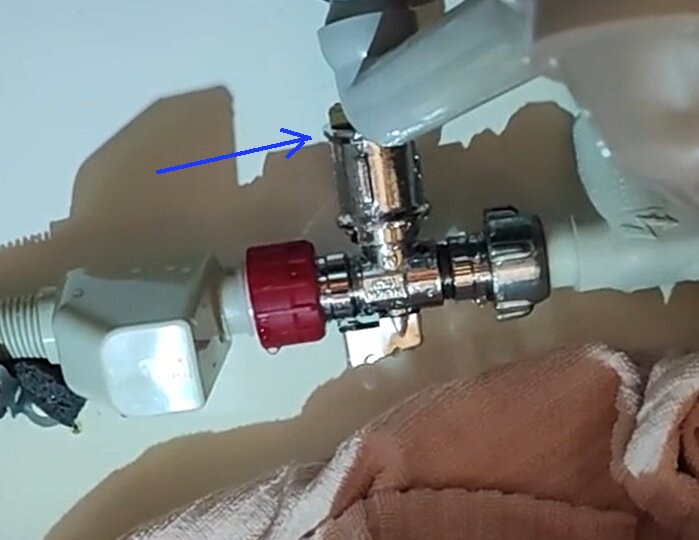 VVS-installation med rörkopplingar, röd ventil och en hand med handskar.