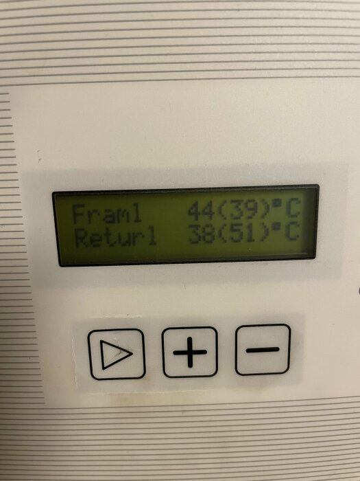 Digital display på en termisk anordning visar temperaturvärden: Framl 44(39)°C, Returl 38(51)°C. Kontrollknappar nedanför.