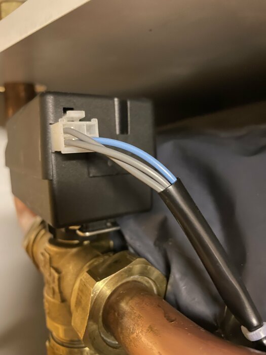 Elkabel kopplad till apparat, mässingsventil, rörledningar, industriell eller VVS-inställning, närbild.