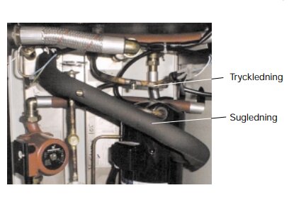 Rörinstallation med etiketterade tryck- och sugledningar, mätare och ventiler, möjligtvis del av värmesystem eller pumpinstallation.